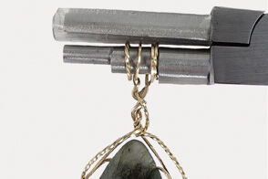 Pliers holding Wire wrapped around pendant